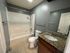 Contemporary bathroom featuring granite countertops, white tiled bathtub, and sleek fixtures.