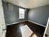 Bright, empty room with modern dark wood flooring and a large window.