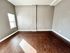 Spacious empty living room with rich hardwood floors and natural light coming through a window.