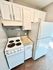 Compact kitchen layout featuring white cabinetry, electric stove, and spacious refrigerator.