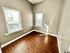 Bright cozy room with two windows and wooden flooring, capturing natural light.