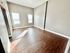 Bright empty room featuring wooden floors and two large windows letting in natural light.