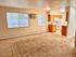 Spacious apartment interior with open-concept living room and kitchen, featuring large windows and warm neutral colors.