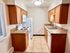 Charming L-shaped kitchen with wooden cabinets, modern appliances, and tiled countertops.