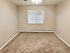 Bright and spacious carpeted bedroom with natural light from a large window.