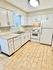 Elegantly designed kitchen with white cabinetry, modern appliances, and stylish tiled flooring.