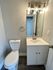 Modern bathroom featuring a sleek white vanity, contemporary lighting, and a pristine toilet.