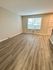 Bright, open room with stylish wood flooring and a large window featuring blinds.