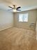 Bright and spacious bedroom with a ceiling fan and carpet flooring.