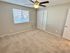 Spacious bedroom with neutral tones, featuring a ceiling fan and ample natural light.