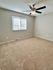 Spacious bedroom with plush carpet and a modern ceiling fan.