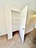 Open white closet with multiple shelves on a plush carpet floor.