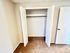 Open white double closet doors with ample storage space in a carpeted room.