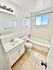 Contemporary bathroom with white fixtures, a sleek vanity, and a tiled bathtub under a bright window.