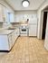 Modern kitchen with white cabinets, sleek countertops, and wood-style flooring.