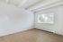 Bright and inviting empty room with large window, elegant laminate flooring, and modern design elements.