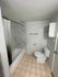 Modern bathroom design featuring elegant marble tiles, a sleek bathtub with a shower curtain, and a compact storage unit.
