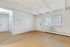 Bright and spacious living room with light wood flooring, large window with blinds, and ample closet space, perfect for a cozy apartment retreat.