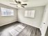 Bright bedroom with large windows, sleek hardwood floors, and a modern ceiling fan creating a cozy atmosphere.