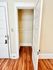 Charming apartment entryway with polished wood flooring and a spacious closet with a classic white door.
