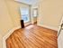 Bright room with hardwood floors, large window, and warm beige walls, perfect for a cozy living space.