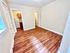 Bright apartment with elegant hardwood flooring, leading to a cozy kitchen area with wooden cabinets and a modern refrigerator.