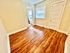 Bright and inviting hallway with rich wooden flooring, beige walls, and a white paneled door.
