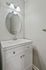 Sleek bathroom with modern vanity, elegant oval mirror, and stylish lighting.