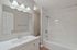 Elegant bathroom with modern fixtures, featuring a sleek vanity, marble tile bathtub, and ambient lighting.