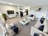 Contemporary living room with sleek white furniture, stylish decor, and an open-plan kitchen, offering a cozy and inviting ambiance.