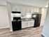 Modern kitchen with sleek black appliances, white cabinets, and elegant wood flooring, creating a stylish culinary space.
