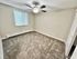 Bright and inviting bedroom with fresh carpeting, a large window, and a modern ceiling fan, perfect for relaxation.
