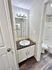 Modern bathroom with elegant dark countertop, bright vanity lighting, and sleek vinyl flooring.