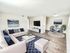 Chic living room with plush white sofas, blue accent pillows, modern decor, and a stylish dining area.