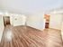 Spacious open-plan living area with elegant wooden floors leading to a bright kitchen with modern cabinetry.