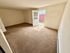 Bright living room with fresh beige carpet, natural light, and a welcoming door leading to a private outdoor space.