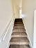 Inviting carpeted staircase with natural light leading to the upper floor of a stylish apartment.