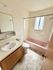 Bright bathroom featuring a classic pink bathtub, elegant tile flooring, and a modern vanity with ample lighting.
