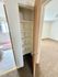 Cozy apartment hallway featuring a spacious storage closet with multiple shelves, adjoining a bathroom with tiled flooring and a carpeted room.