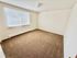 Bright, spacious bedroom with soft carpet and large window letting in natural light, perfect for relaxation and personalization.