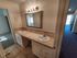 Elegant bathroom with double sinks, ample counter space, and modern lighting. Carpeting and a view of the balcony in adjacent rooms add to the allure.