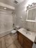 Bright modern bathroom featuring elegant tile flooring, a sleek vanity, and a bathtub with a shower.