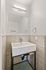 Modern bathroom corner with elegant white sink, sleek rectangular mirror, and stylish tiled walls.