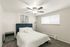 Elegant bedroom with plush navy headboard, modern ceiling fan, and chic decor, offering a serene and inviting atmosphere.