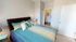 Bright and cozy bedroom with stylish blue and beige bedding, elegant decor, and an en-suite bathroom.