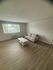 Bright living room with large window, modern grey sofa, and sleek wooden floors creating a spacious, inviting atmosphere.