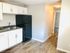 Modern kitchen with sleek black refrigerator, crisp white cabinets, and elegant laminate flooring.