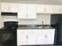 Modern kitchen with sleek black appliances, white cabinets, and a dual sink, offering ample storage and countertop space.