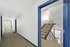 Bright apartment hallway with modern blue door frames, leading to a carpeted staircase and well-lit corridor.