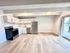 Bright modern kitchen with stainless appliances, sleek white cabinets, and open layout leading to a balcony.